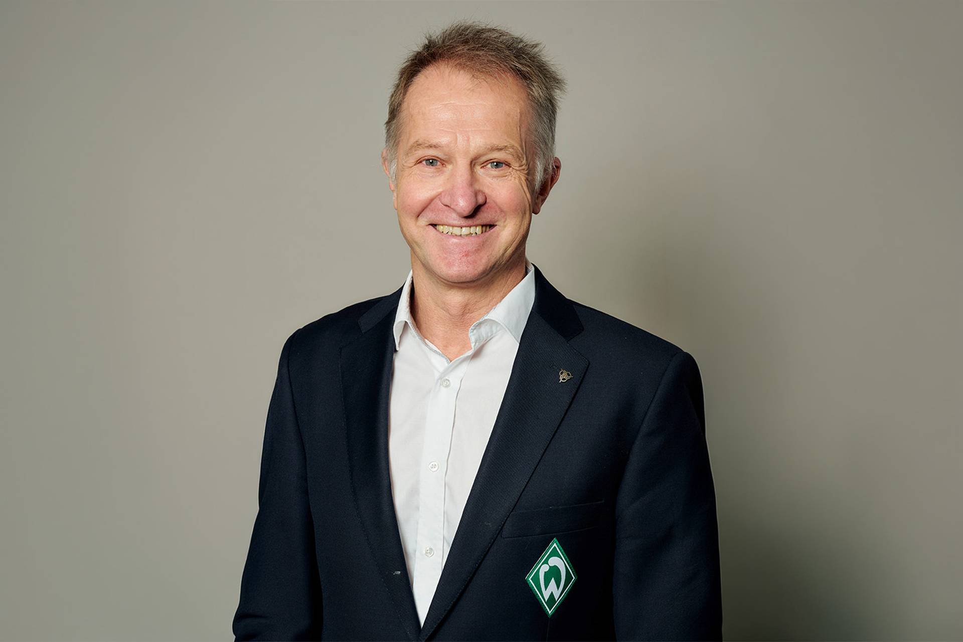 Radek Lewicki lächelt in seinem schwarzen Anzug in die Kamera.