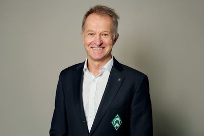 Radek Lewicki lächelt in seinem schwarzen Anzug in die Kamera..