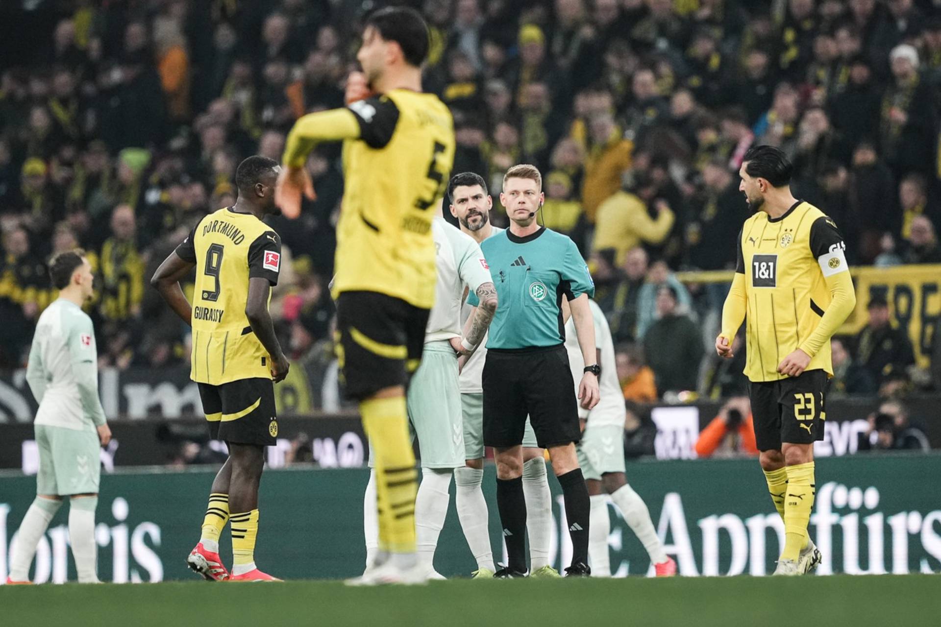 Christian Dingert auf dem Platz neben Spielern.