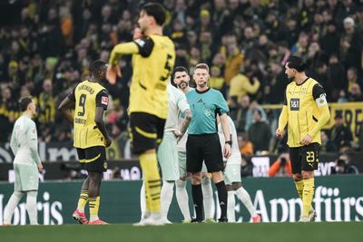 Christian Dingert auf dem Platz neben Spielern.