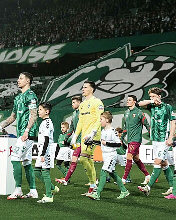 Michael Zetterer mit einem Einlaufkind an der Hand beim Einlaufen in das Weserstadion gegen Augsburg