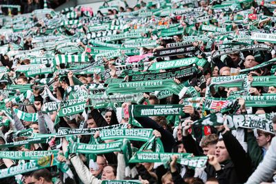 Die Fans in der Kurve halten ihre Werder-Schals hoch.