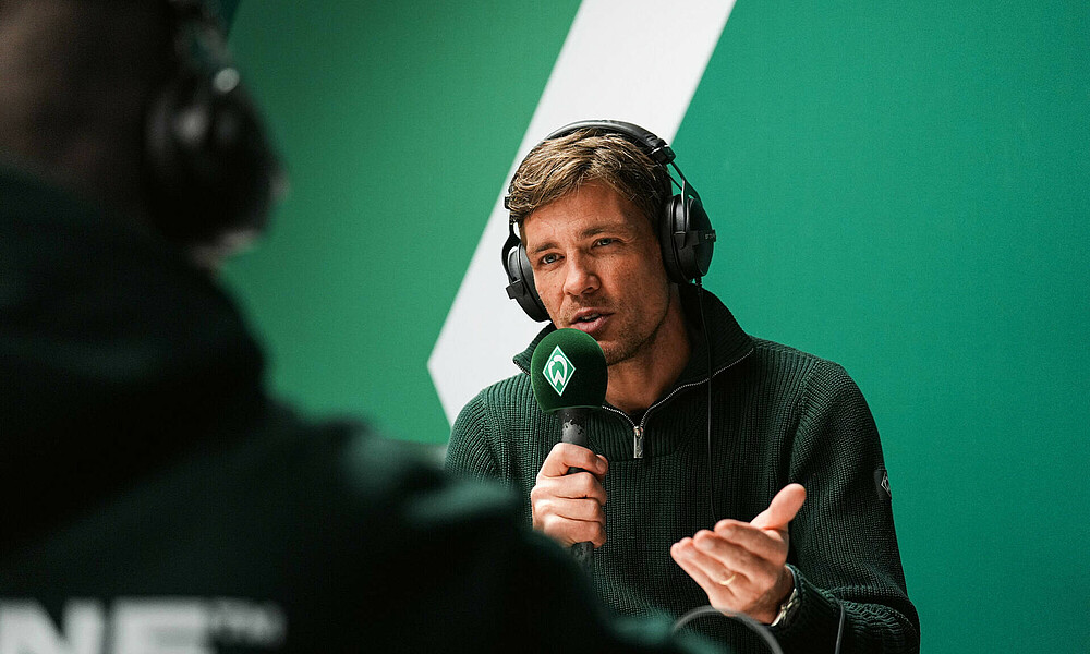 Clemens Fritz im Podcast mit einem Mikrofon in der Hand.