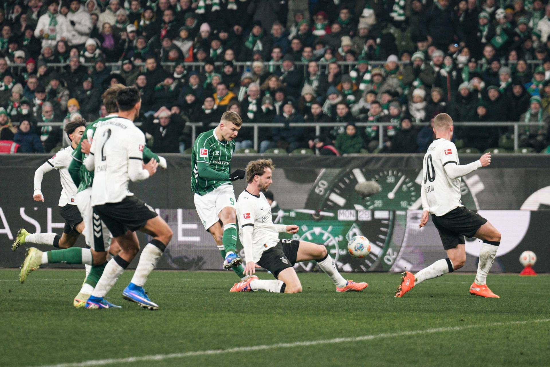 Keke Topp holt zum Schuss aus, die Gladbacher versuchen vergebliche das zu verhindern.