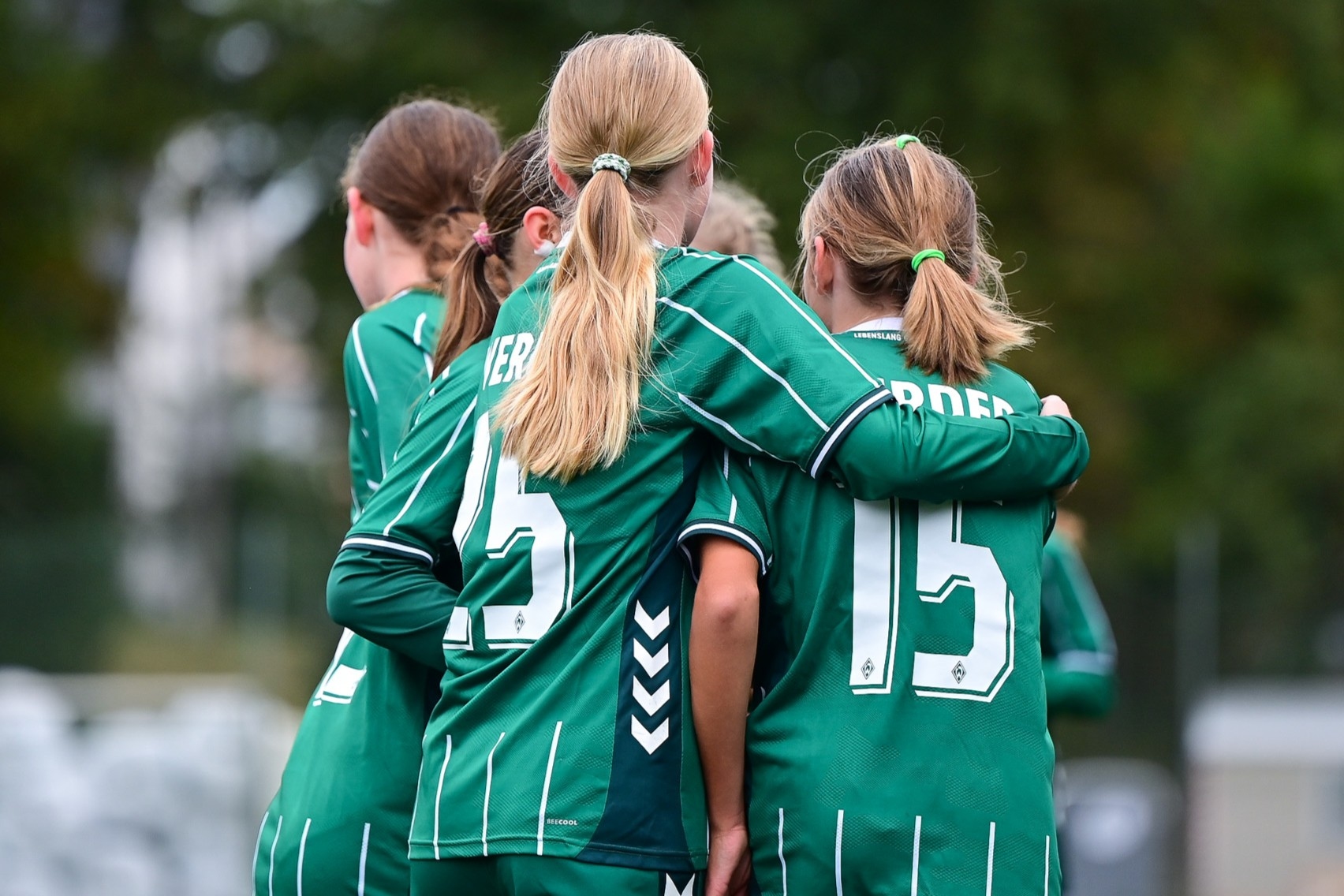 Die Spielerinnen der U15 umarmen sich in ihren grün-weißen Trikots.
