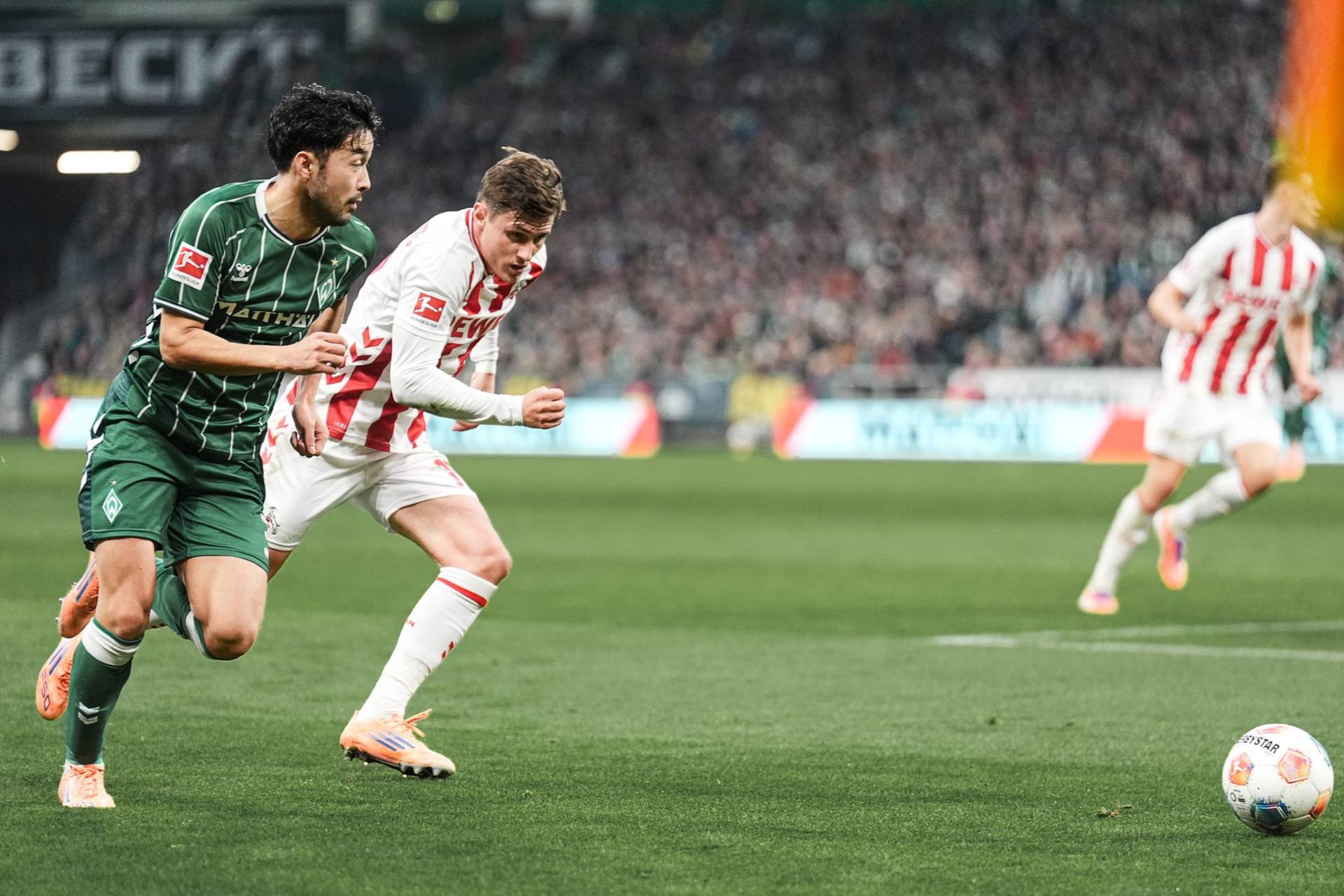 Sugawara im Laufduell mit einem Kölner mit Blick auf den Ball.