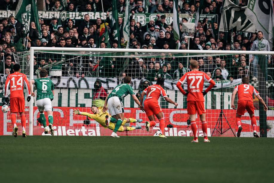 Harry Kane schießt einen Elfmeter, Mio Backhaus streckt sich, kommt aber nicht an den Ball. Im Hintergrund Werder-Fans.