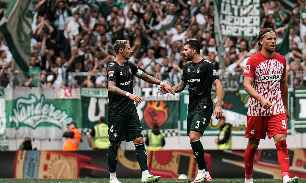 Marco Friedl und Anthony Jung klatschen auf dem Spielfeld ab. 