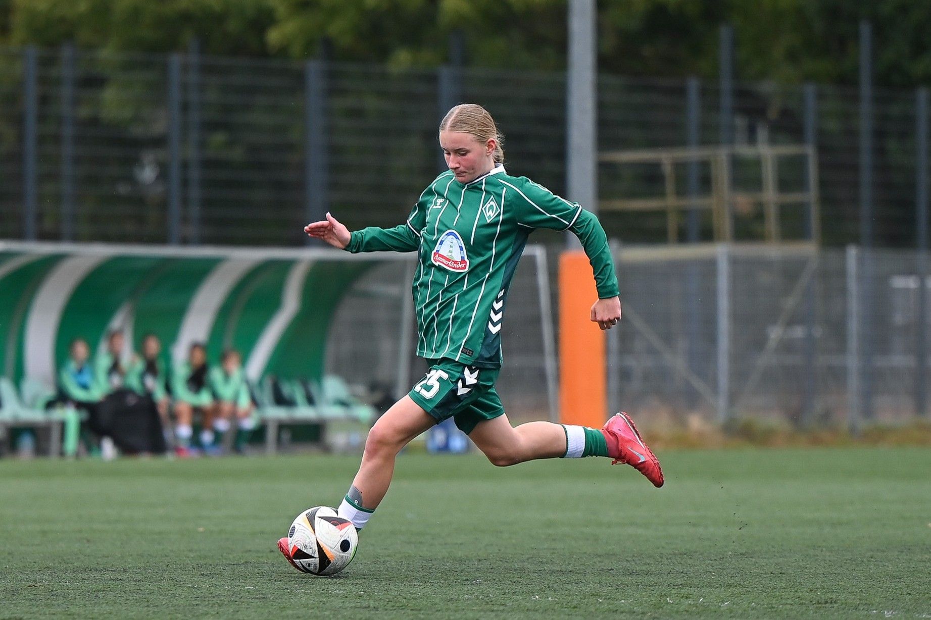 Eine U15-Spielerin im grünen Dress dribbelt mit dem Ball
