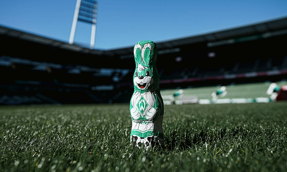Ein grün-weißer Osterhase steht auf dem Rasen im wohninvest WESERSTADION.