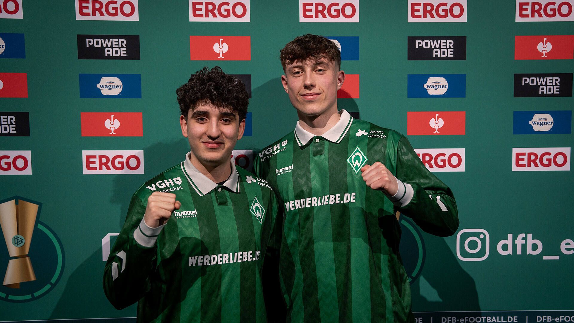 Berkay und Henning stehen vor einer Sponsorenwand.