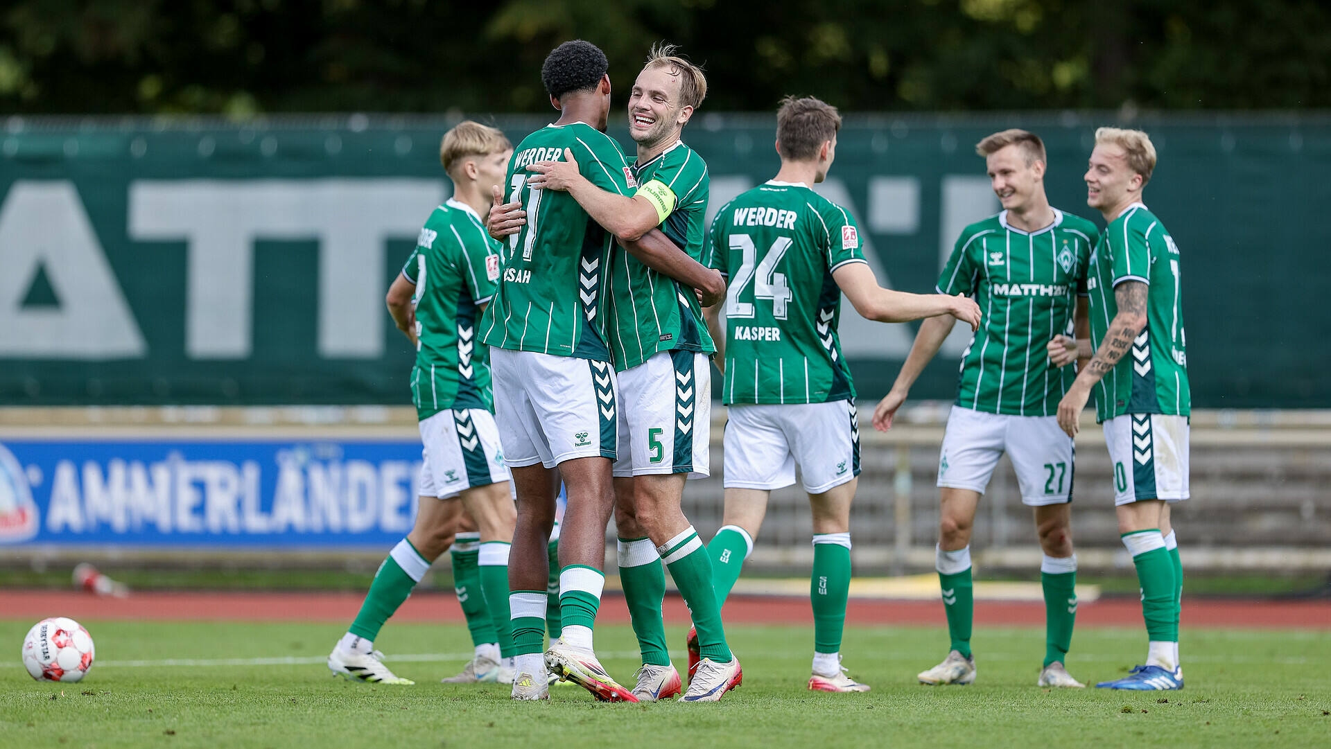 Cimo Rücker und Salim Musah umarmen sich, im Hintergrund laufen weitere Spieler, die sich freuen.