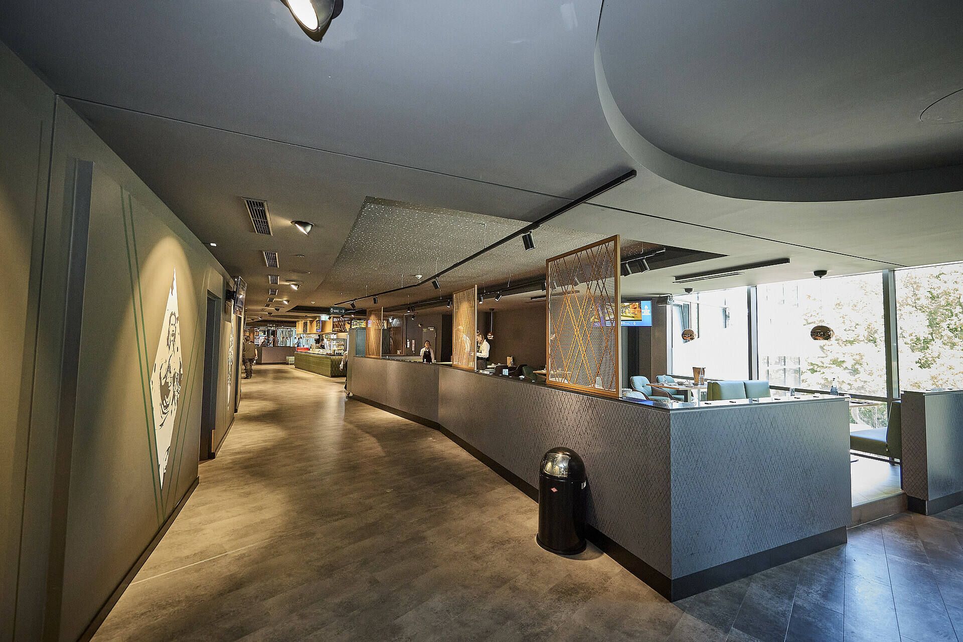 Moderne Hotellobby mit elegantem Design, geschwungener Rezeption, Holzakzenten und großen Fenstern, die Tageslicht hereinlassen.