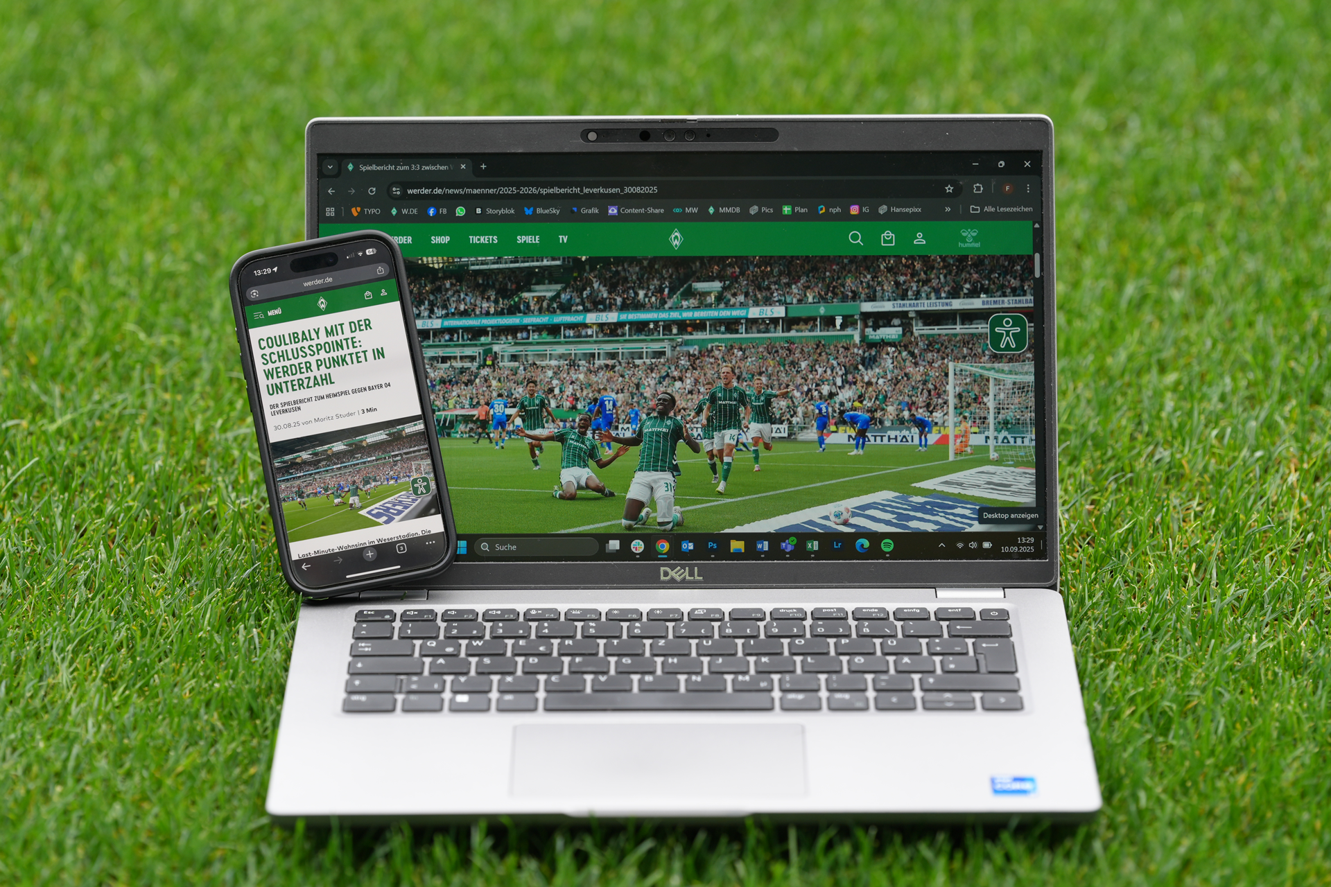 Ein Laptop und ein Smartphone zeigen ein Fußballspiel auf einem Rasenfeld und geben eine Spielszene mit Spielern in Aktion wieder.