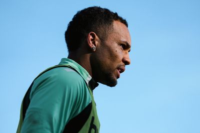Das Profil eines Mannes in einem grünen Sporttrikot vor strahlend blauem Himmel; er wirkt konzentriert und gelassen.
