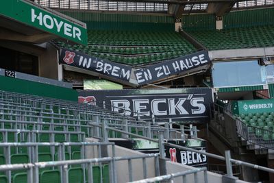 Leere Stadionplätze mit Transparenten mit der Aufschrift „IN BREMEN ZU HAUSE“ sowie Werbung für Beck’s und WERDER.TV.
