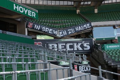 Leere Stadionplätze mit Transparenten mit der Aufschrift „IN BREMEN ZU HAUSE“ sowie Werbung für Beck’s und WERDER.TV.