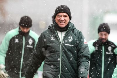 Horst Steffen in einer grünen Jacke und einer schwarzen Mütze lächelt bei Schneefall, im Hintergrund stehen zwei weitere Personen in ähnlicher Kleidung.