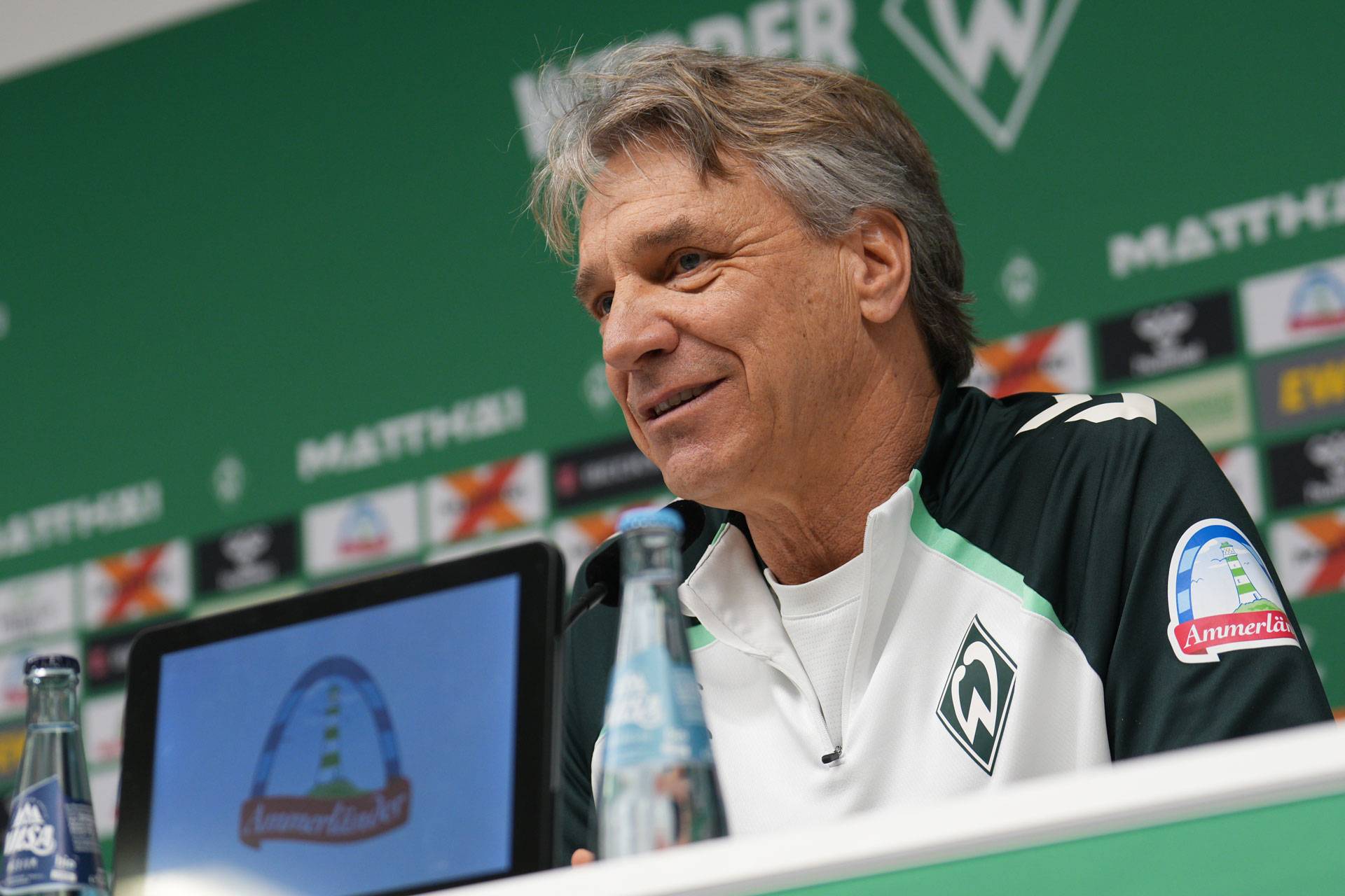 Horst Steffen sits at the podium in the press conference room, smiling.