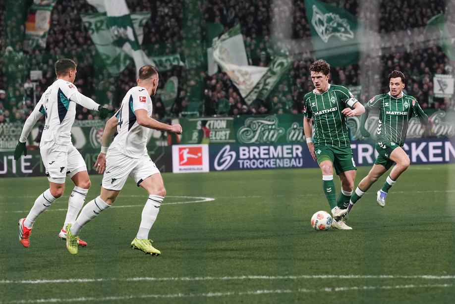 Jens Stage im Dribbling gegen Hoffenheim. Zwei Gegenspieler schauen zu.