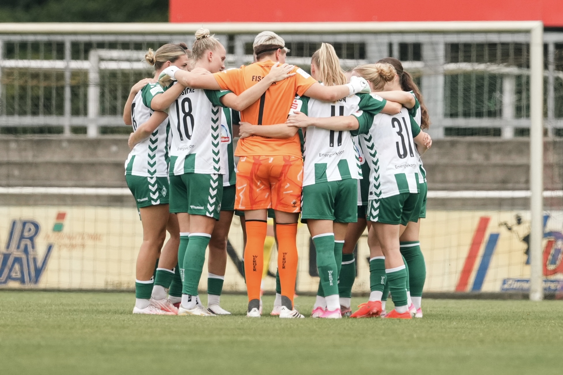 Die WERDERFRAUEN bilden einen Mannschaftskreis im Heimtrikot.