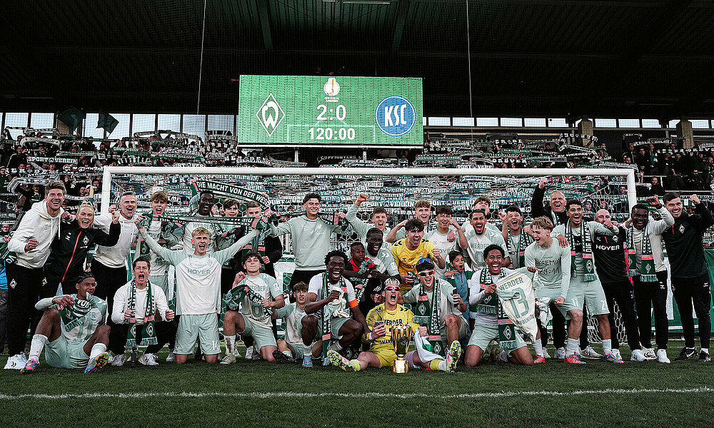 Die Mannschaft jubelt vor der Kurve mit dem Pokal