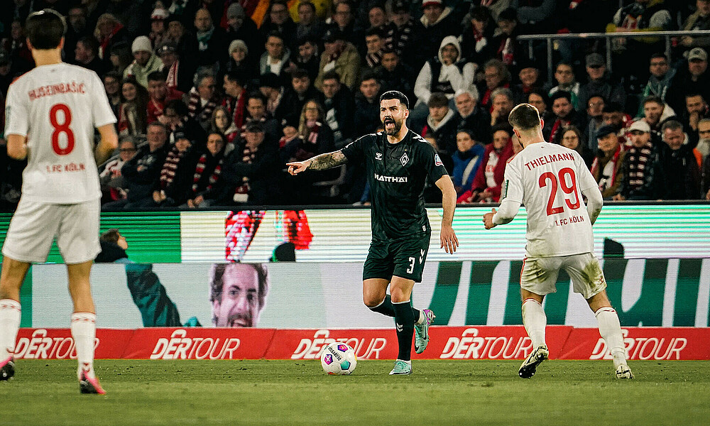Anthony Jung mit Ball am Fuß zwischen Gegenspielern. 