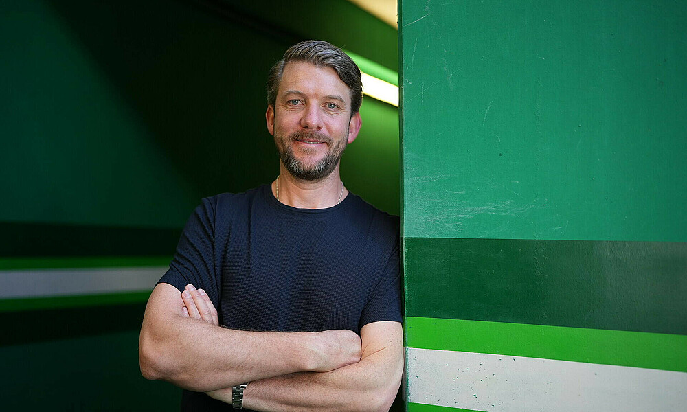 Peter Niemeyer lehnt mit verschränkten Armen an einer Wand. 