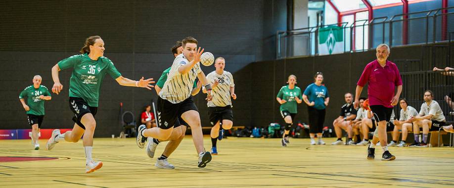 Handballspiel mit Spieler*innen in grünen und weißen Trikots kämpfen um den Ball