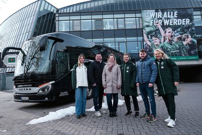 Der neue Mannschaftsbus steht vor dem Weserstadion, davor stehen Mitarbeiter vom Busunternehmen Barth gemeinsam mit Wirtz, Dieckmann und Kromp.