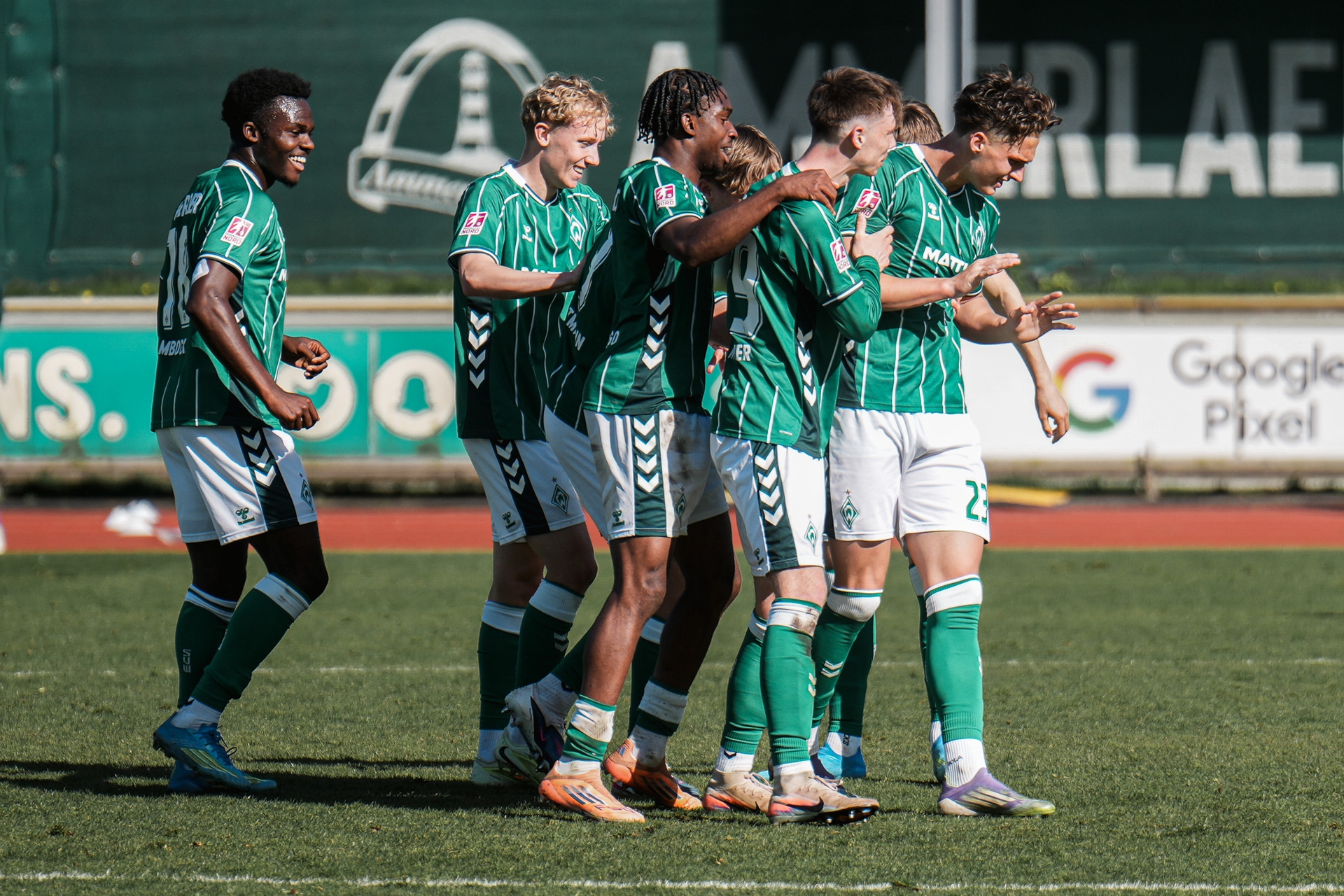 Kevin Manthey und einige andere Spieler des SV Werder umarmen sich zum Jubel.