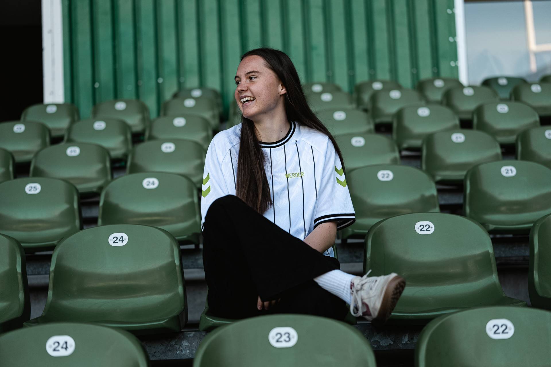 Lilli Purtscheller sitzt im Weserstadion und schaut lachend nach links.