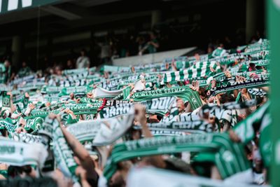 Bei einem Fußballspiel schwenken die Fans begeistert grün-weiße Schals und bilden so im Stadion ein lebhaftes Meer aus jubelnden Fans.