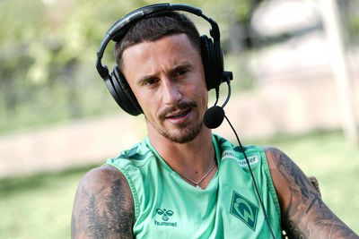 Marco Friedl in einem Werder-Shirt mit einem Headset auf.