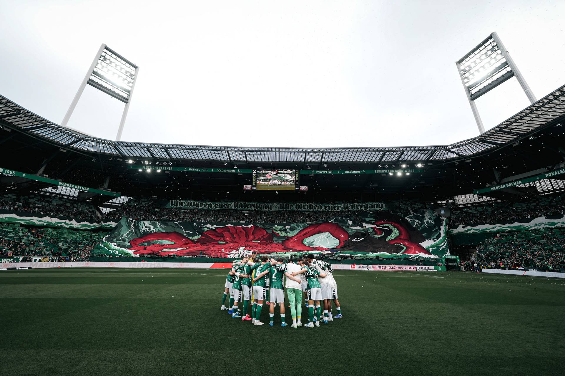 Der Mannschaftskreis vor der Kurve, in der eine Choreo vorgetragen wird.