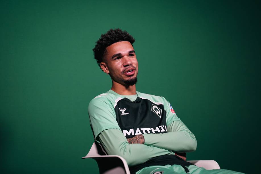 Justin Njinmah sitzt mit verschränkten Armen im Interview.