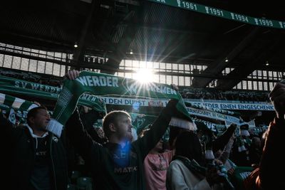 Fans mit Werder-Schal auf der Tribüne.