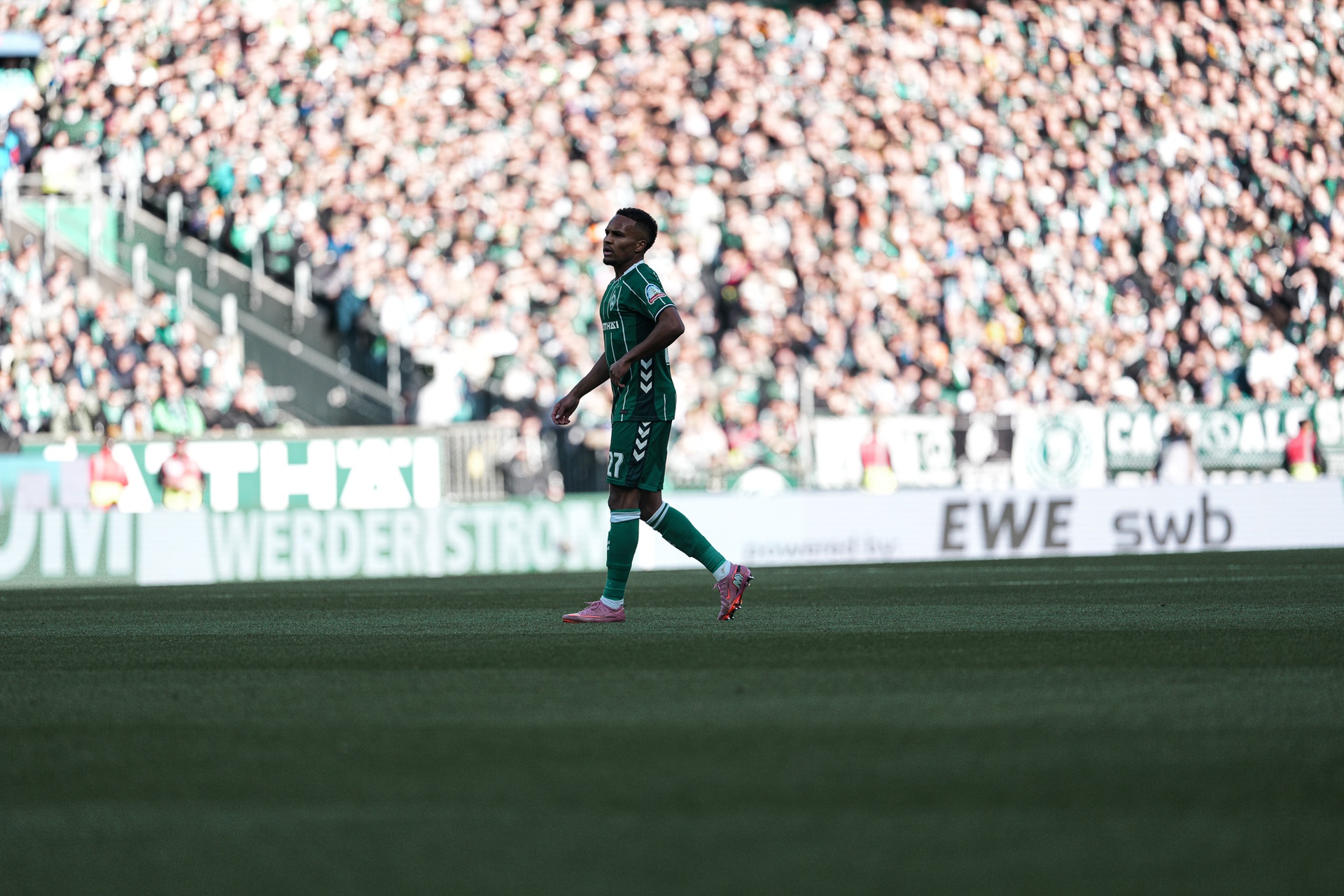 Felix Agu on the pitch in a Werder jersey, with the crowd in the background.