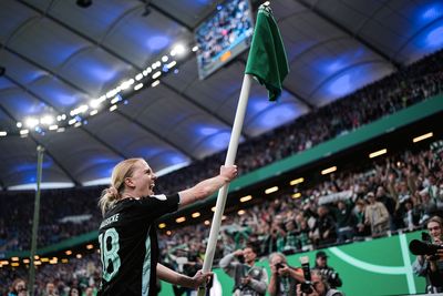 Lina Hausicke hält die Eckfahne nach oben, auf der ein Werder-Shirt angebracht ist.