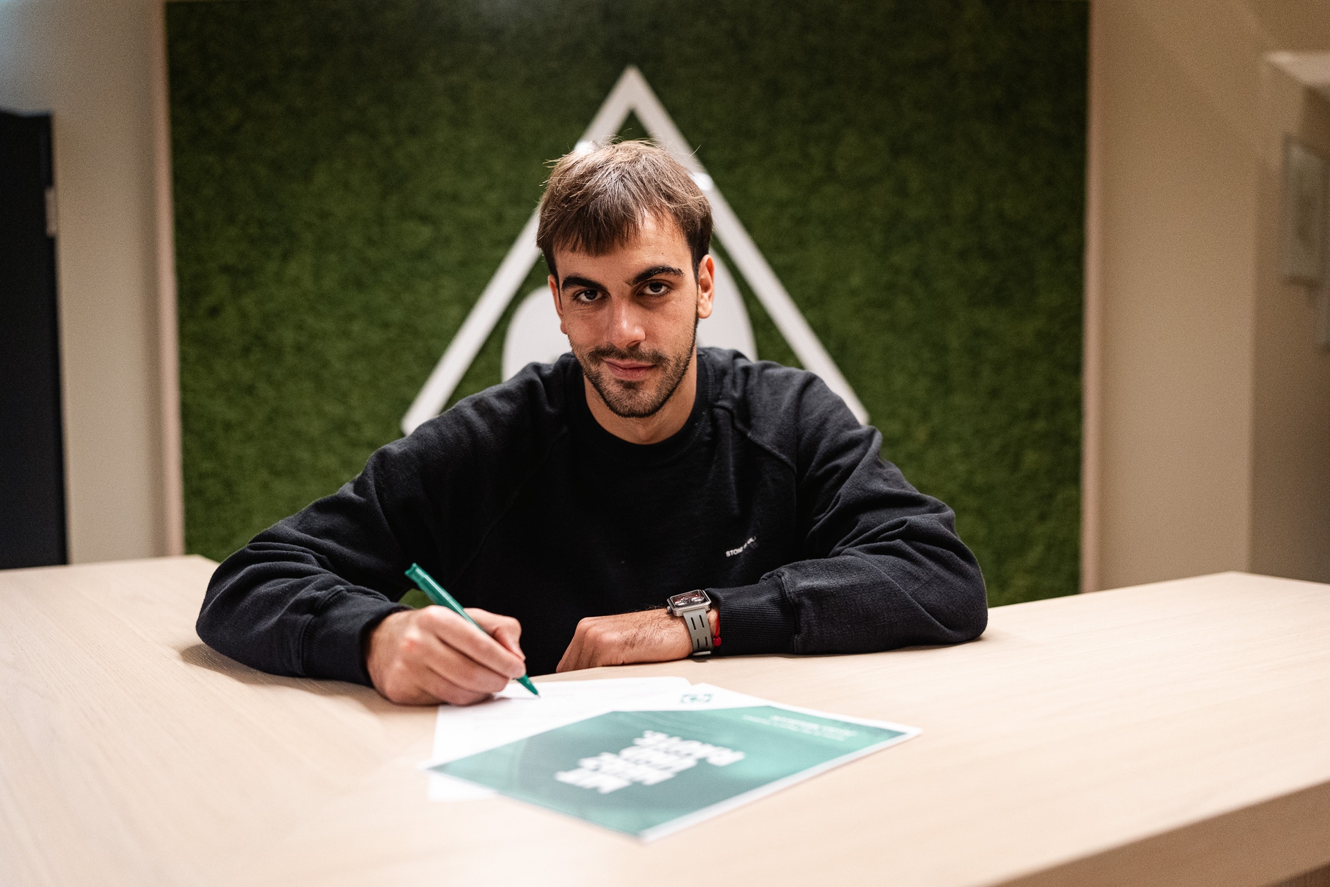 Milosevic bei der Vertragsunterschrift vor einer Werder-Raute.