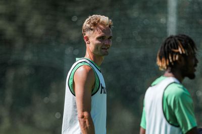 Zwei Sportler in ärmelloser Sportbekleidung beim Training im Freien; einer blickt in die Kamera, während sich das Sonnenlicht auf seiner Haut spiegelt.
