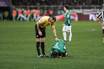 Sören Storks beugt sich über Samuel Mbangula, der auf dem Boden liegt.