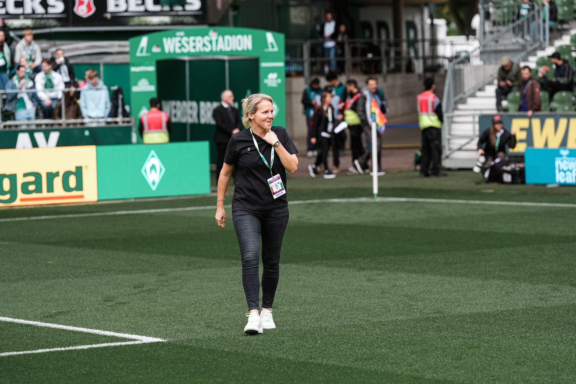 Trainerin Fritzy Kromp läuft über den Rasen des Weserstadions und lächelt.