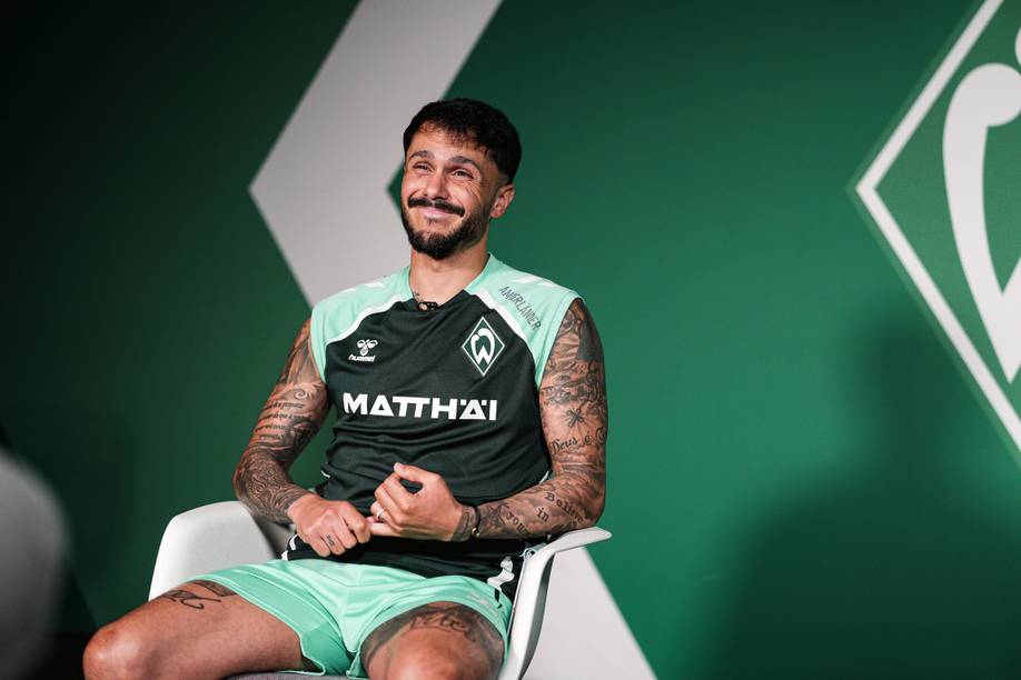Leonardo Bittencourt sitting down for an interview in front of a green wall.