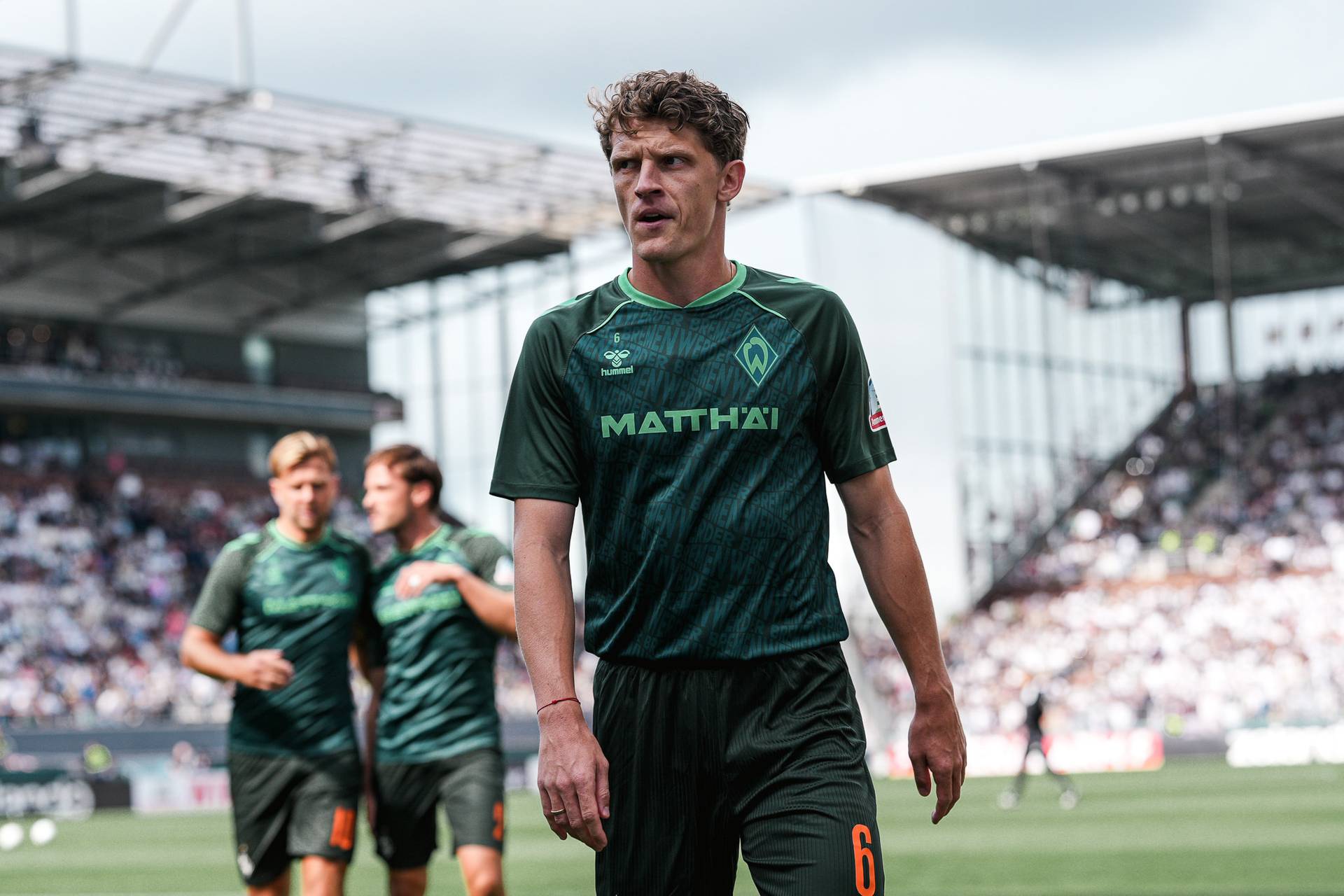 Jens Stage geht über den Platz am Millerntor in einem Werder-Aufwärmshirt.