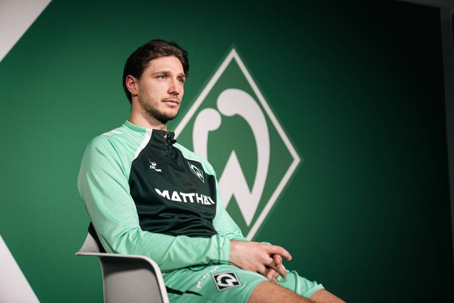 Niklas Stark sitzt im Interview vor einer Werder-Raute.