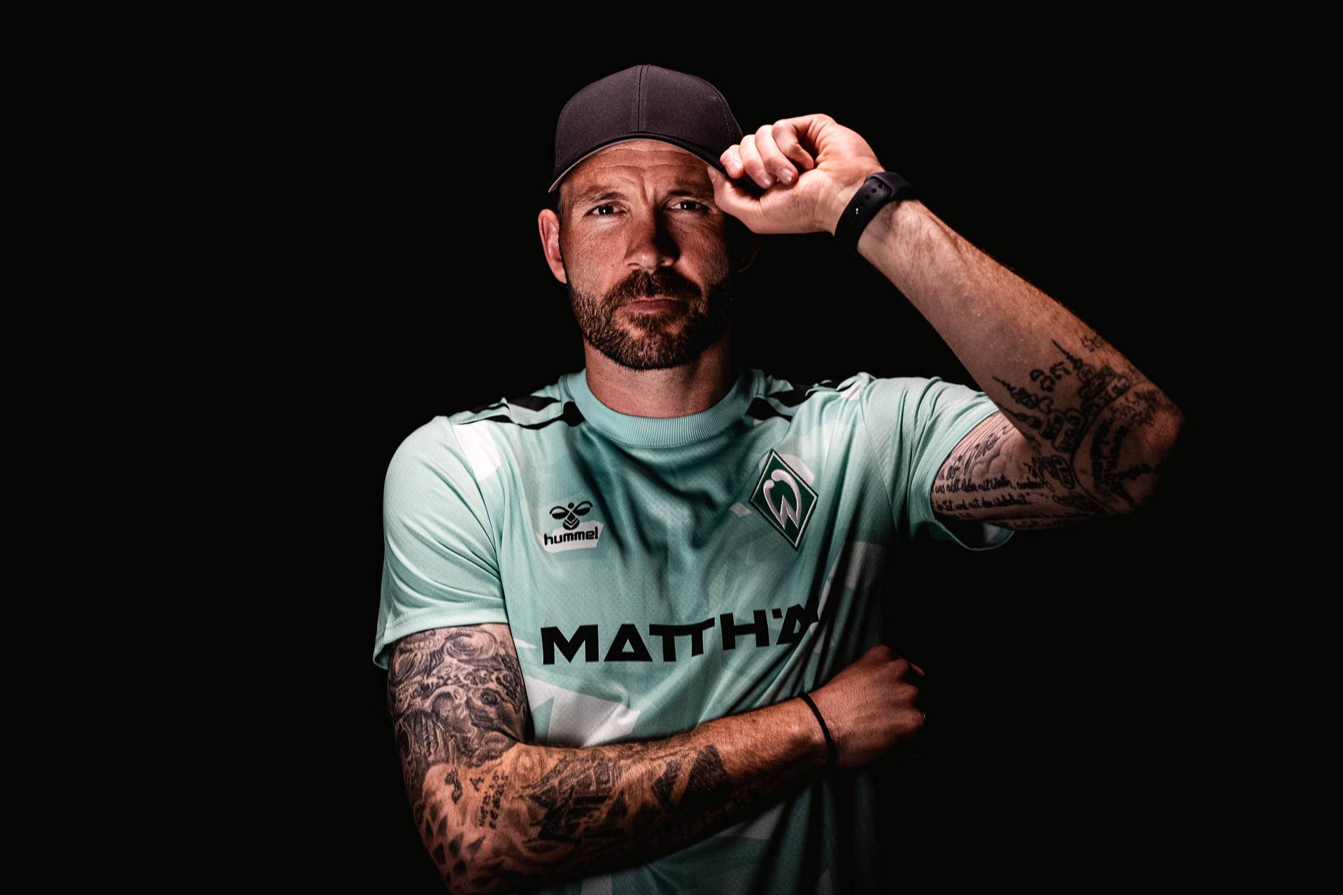 Markus Kolke holds the brim of his black baseball cap.