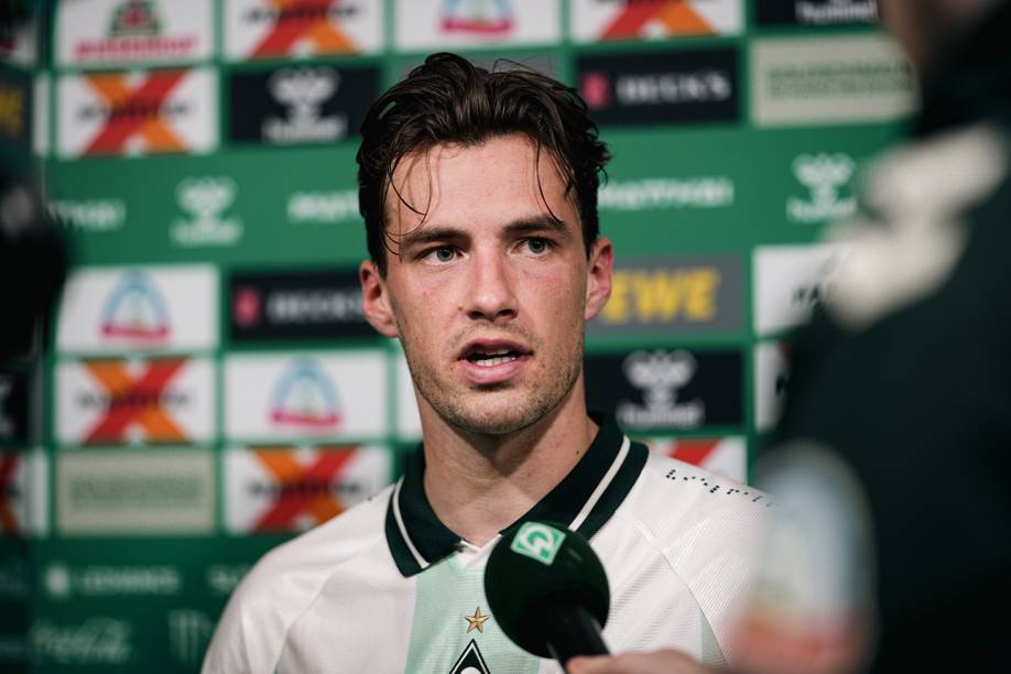 Olivier Deman an einem Werder-Mikrofon in der Mixed Zone.