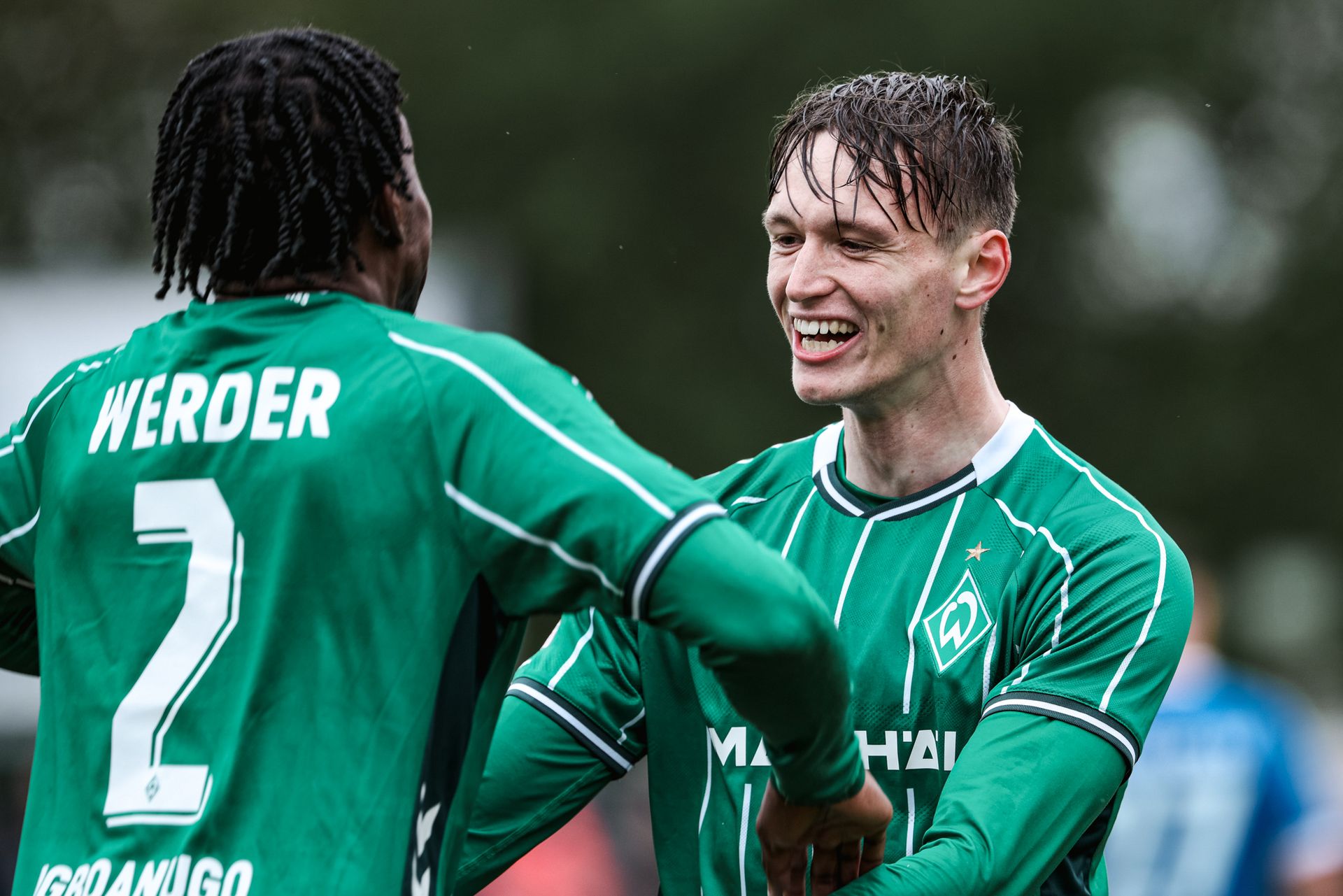 Dominik Kasper steht mit einem lächelnden Gesicht vor einem Mitspieler.