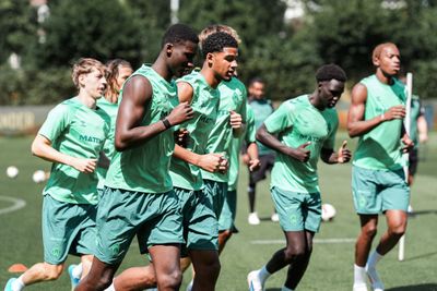 Eine Gruppe von Fußballspielern in grünen Trikots und Shorts, die während einer Trainingseinheit auf einem Rasenplatz joggen.
